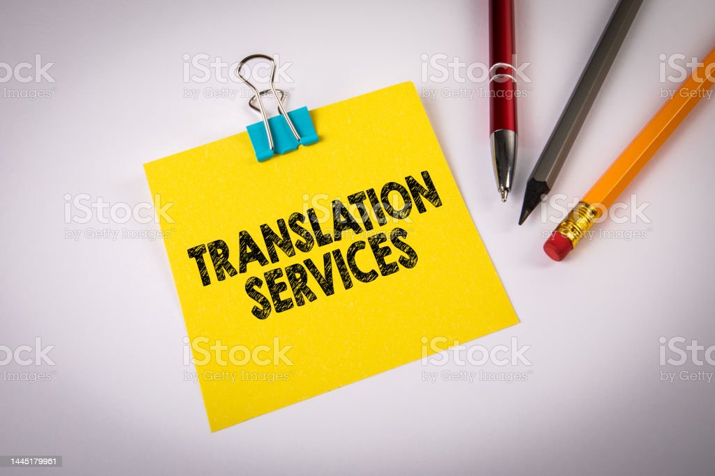 TRANSLATION SERVICES. Text on yellow sticky note. White office desk.